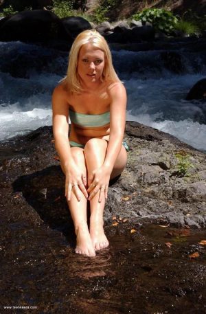 Young blonde removes her bikini to pet her twat on slippery rocks