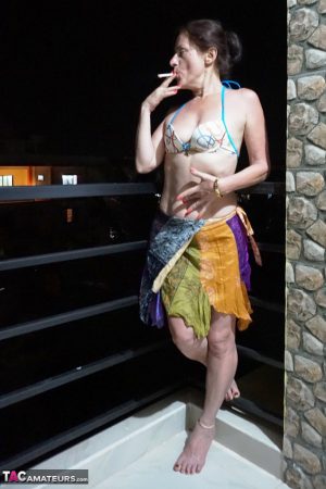 Mature woman Diana Ananta smokes a cigarette while exposing her snatch