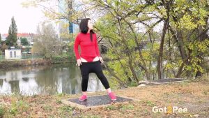 Dark haired girl Corin pulls down leggings for a pee on a grate by the river