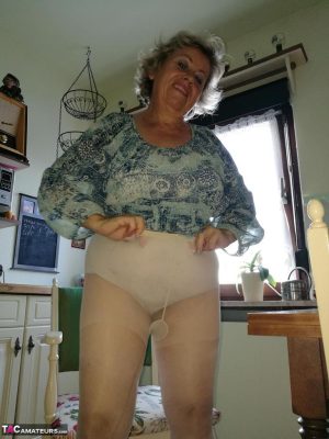 Horny granny Caro sticks a banana inside her natural pussy on kitchen chair